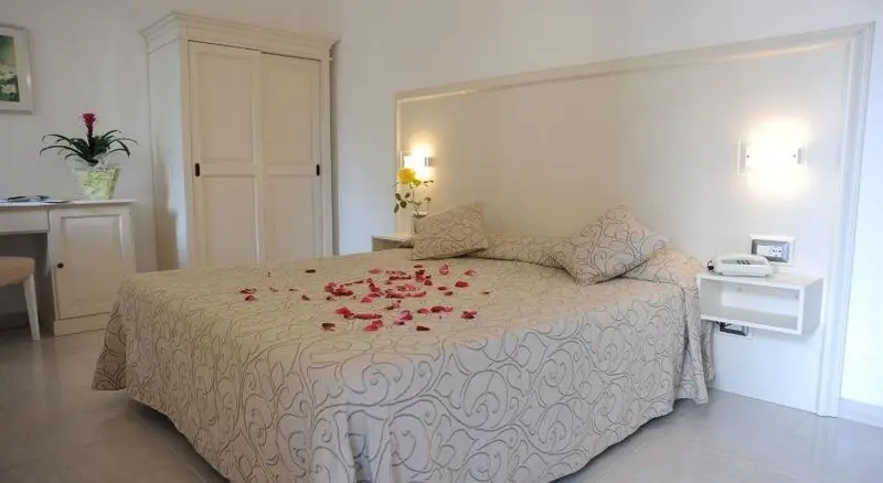 Une chambre lumineuse avec un grand lit décoré de pétales de fleurs.