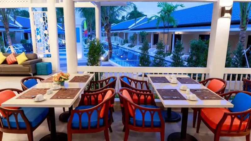 Tables de restaurant en plein air avec des chaises colorées et une vue sur une piscine.