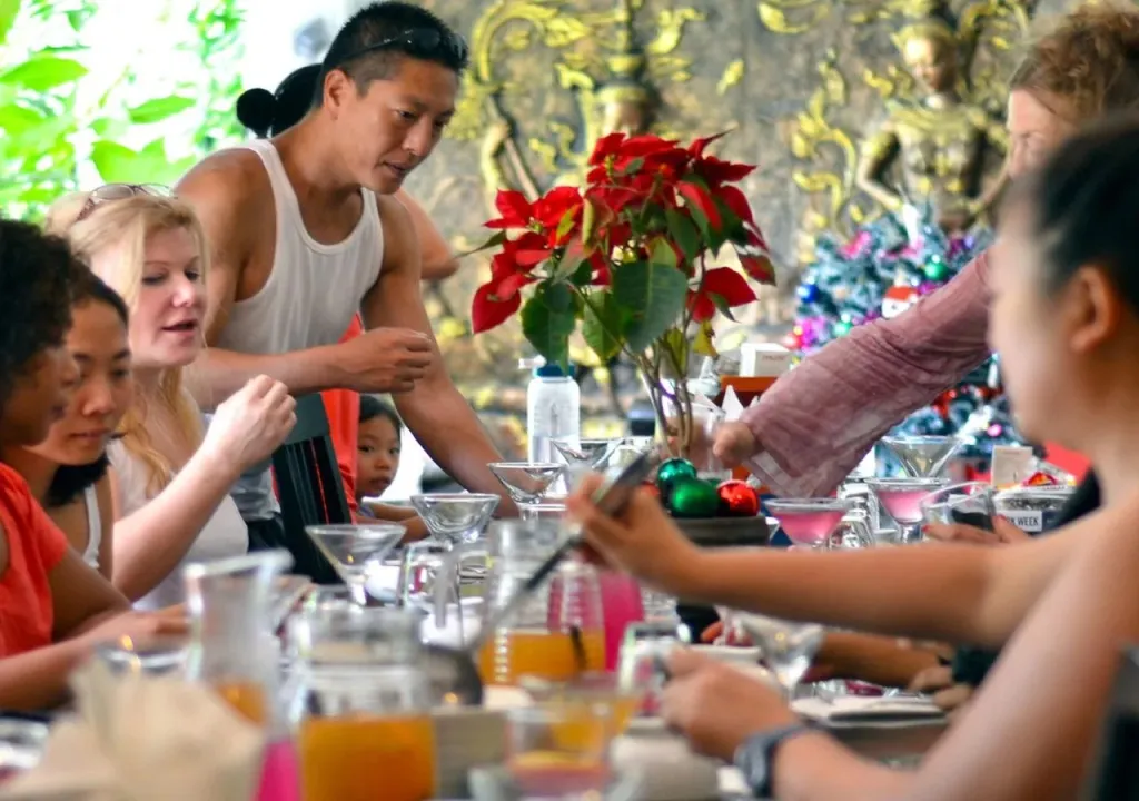 Une table est dressée avec des verres et des boissons, entourée de convives.