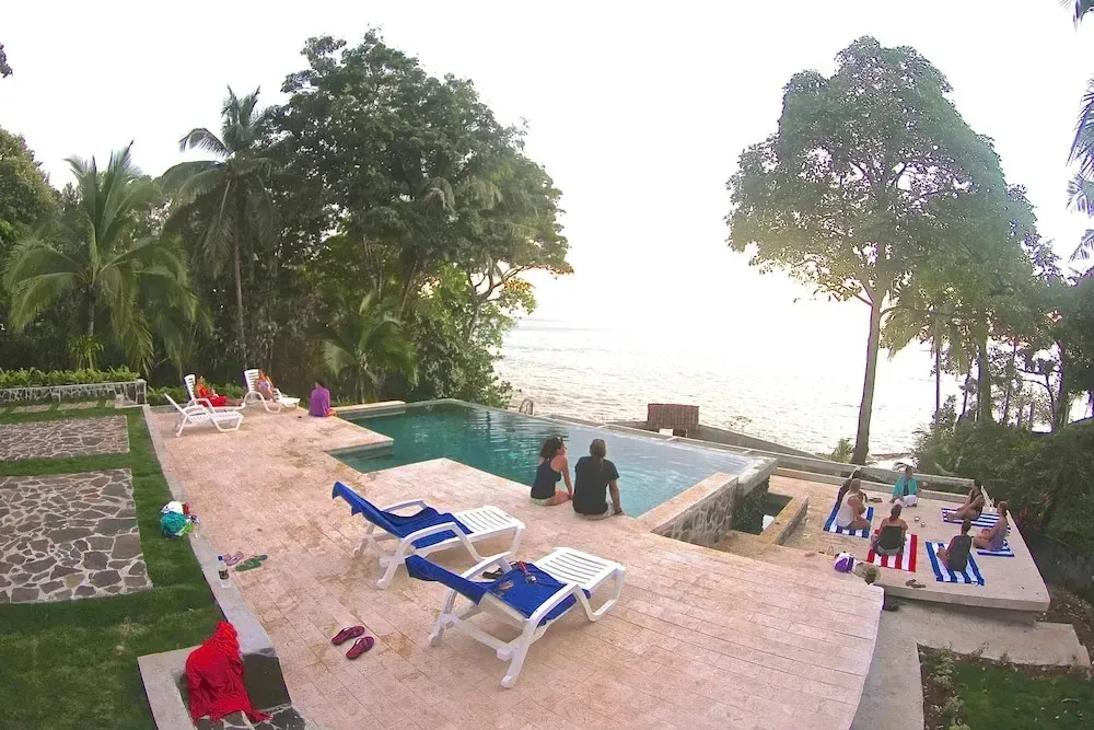 Une piscine bordée d'une terrasse ensoleillée offre une vue sur la mer.