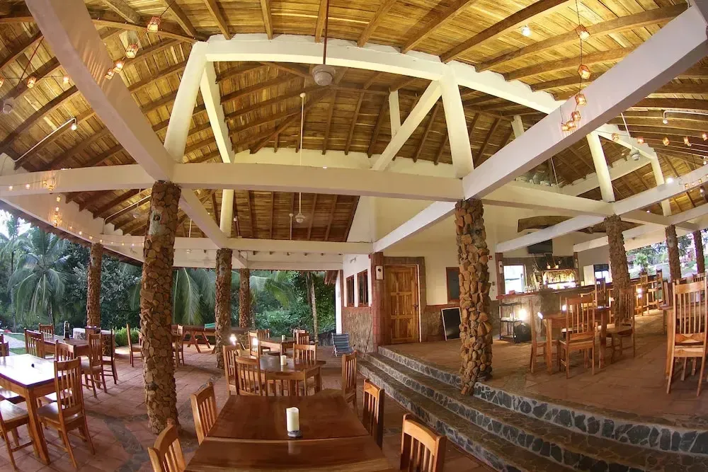 Une salle à manger extérieure avec des tables en bois et une structure en bois au plafond.