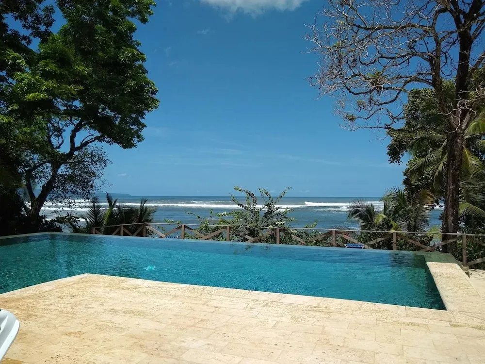 Une piscine à débordement offre une vue sur la mer et la végétation luxuriante.