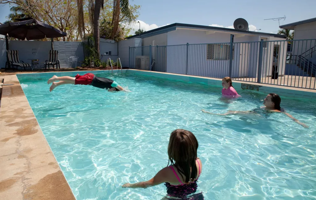 Des baigneurs s'amusent dans une piscine ensoleillée.