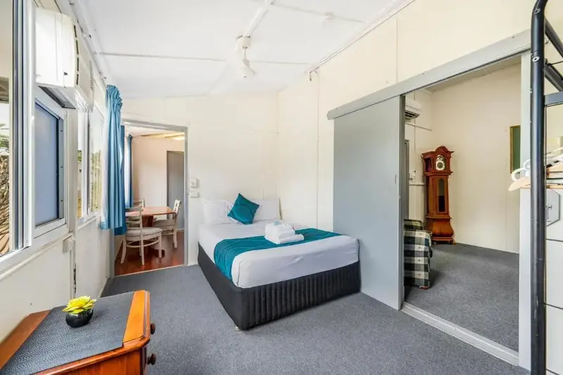 Une chambre lumineuse avec un lit fait et un espace repas attenant.