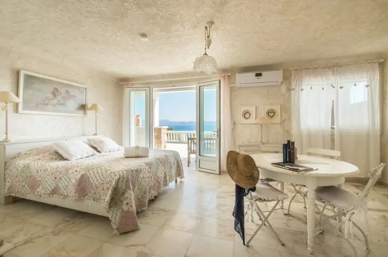 Une chambre lumineuse s'ouvre sur une vue mer par de grandes baies vitrées.