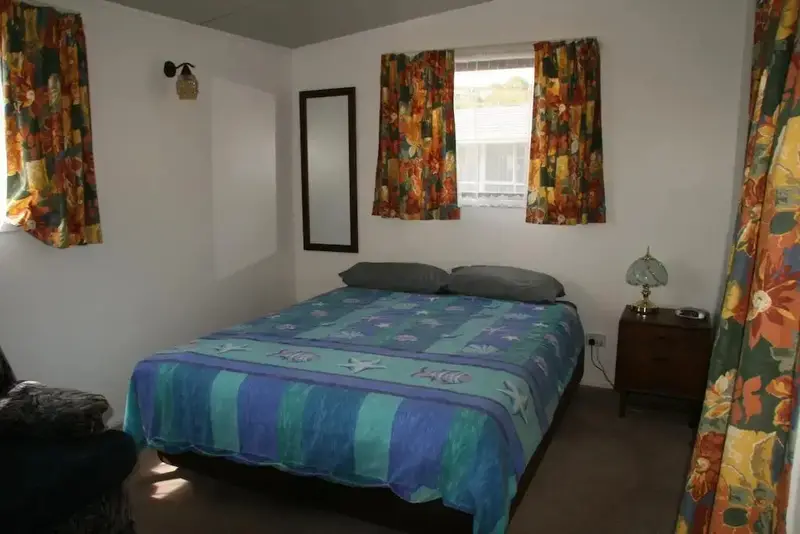 Une chambre lumineuse avec un lit recouvert d'une courtepointe colorée et des rideaux à motifs.