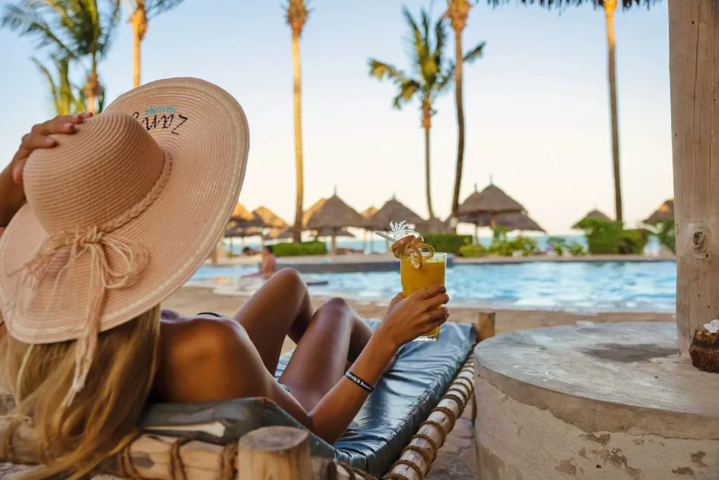Une personne se détend au bord d'une piscine avec un cocktail.