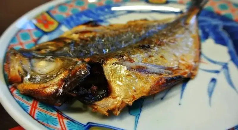 Deux poissons grillés sont servis sur une assiette décorée.