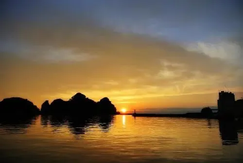 Coucher de soleil sur une piscine avec des ilots rocheux en arrière-plan.
