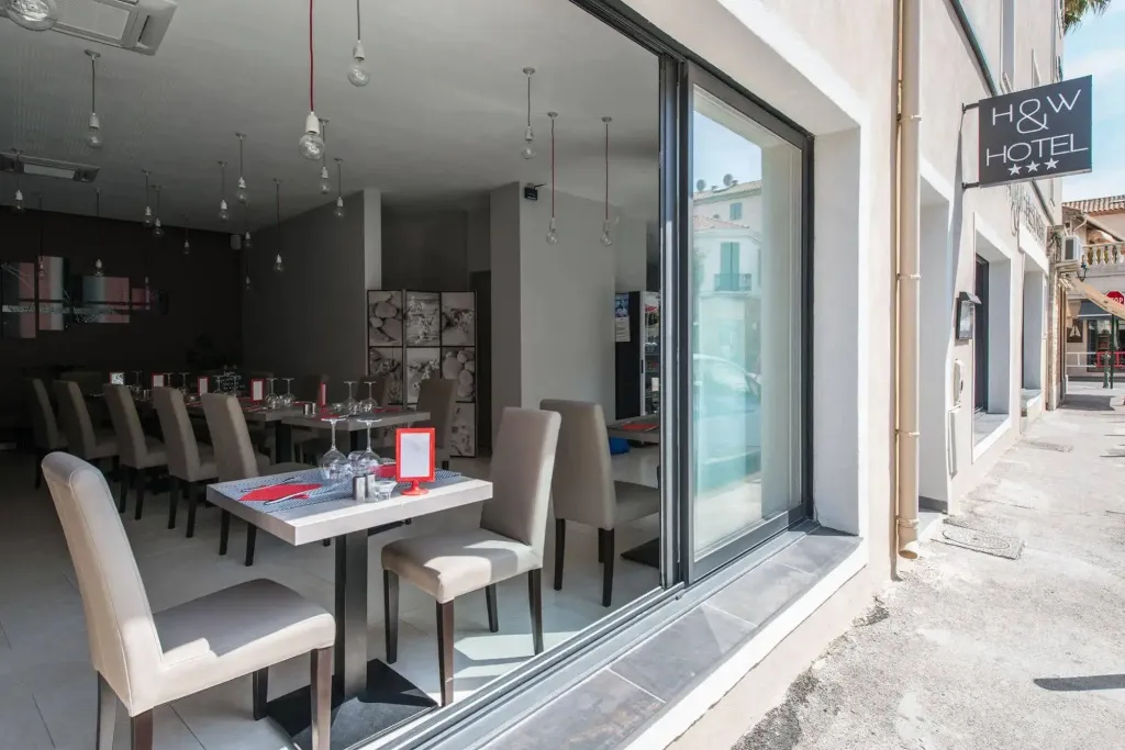 Une salle de restaurant lumineuse avec des tables dressées et des chaises beiges.