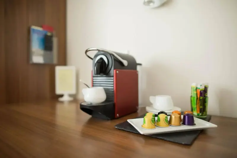 Une machine à café et des capsules colorées sont disposées sur une table en bois.