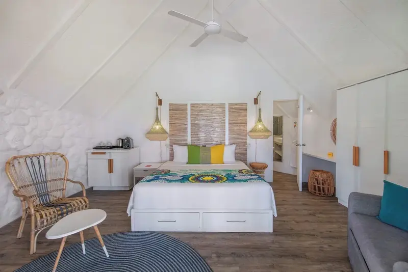 Une chambre lumineuse avec un grand lit et un coin salon.