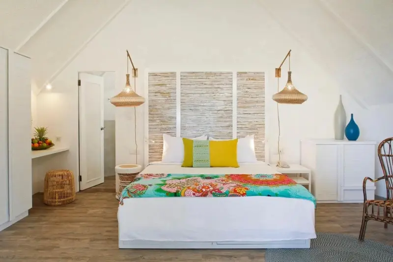 Une chambre lumineuse avec un grand lit recouvert d'une courtepointe colorée.