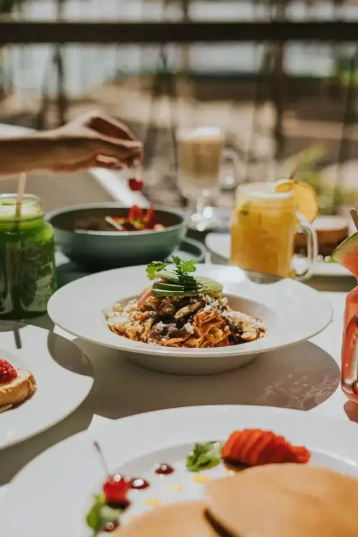 Une table est dressée avec des plats colorés et des boissons fraîches.