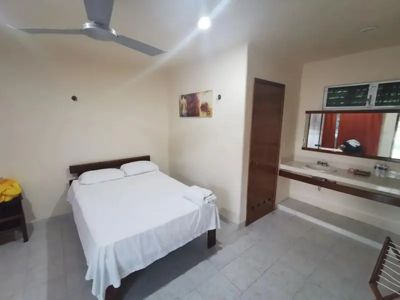 Une chambre lumineuse avec un grand lit et un coin lavabo.