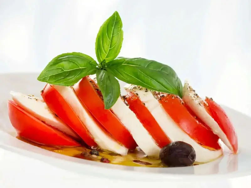 Assiette de tomates et de mozzarella décorée de basilic frais.