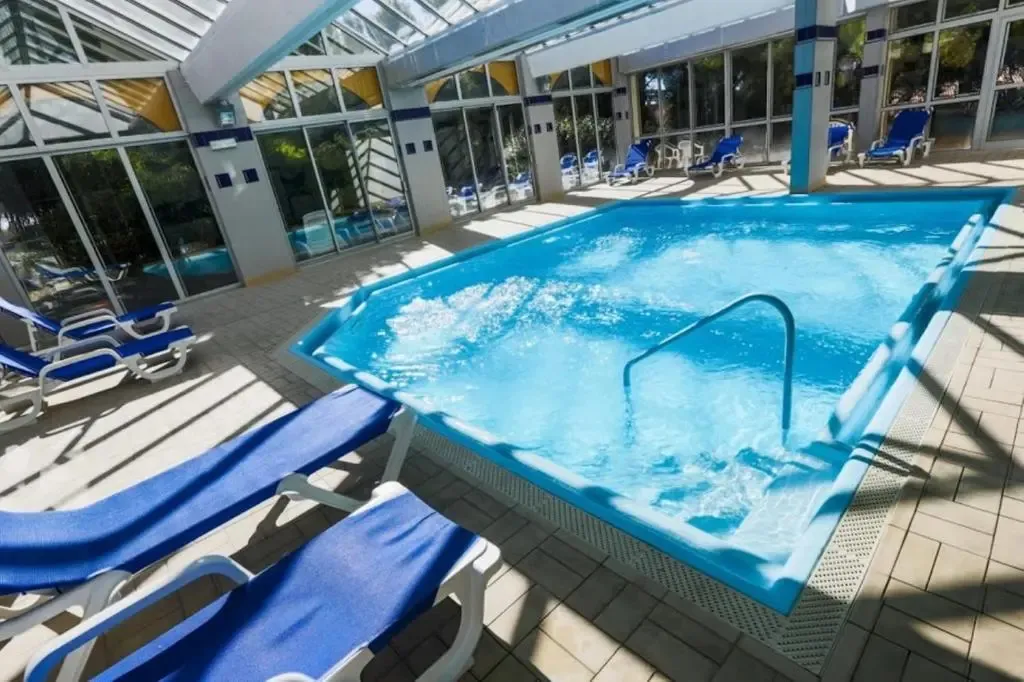 Une piscine intérieure lumineuse avec des transats bleus.