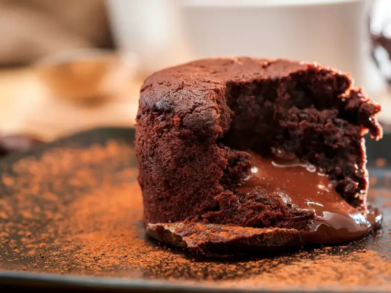 Un dessert au chocolat coulant est présenté sur une assiette saupoudrée de cacao.