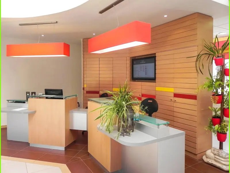 Un comptoir d'accueil moderne avec des plantes vertes et un éclairage orangé.