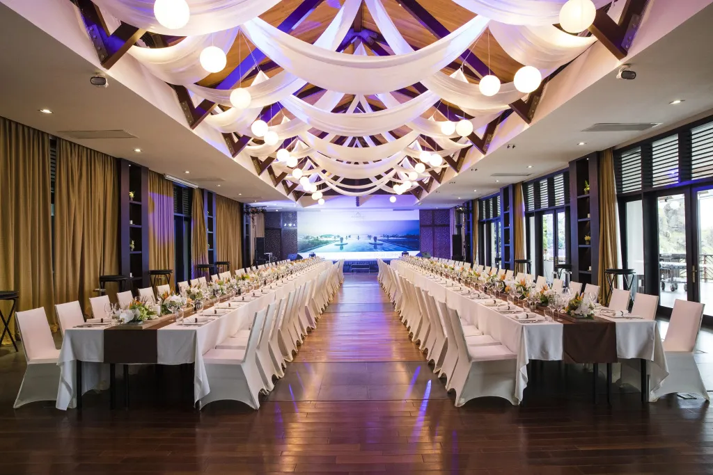 Longue salle de réception avec tables dressées pour un banquet.
