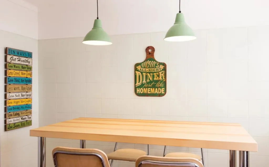 Une table en bois clair est entourée de chaises dans une salle lumineuse.