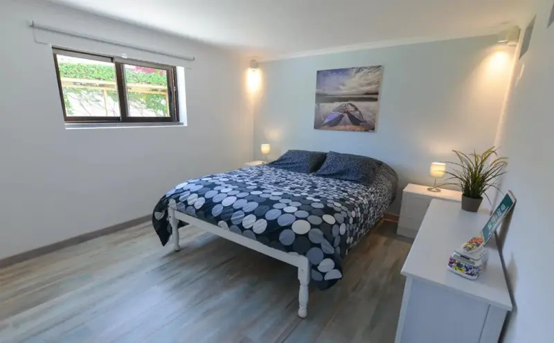 Une chambre lumineuse avec un lit recouvert d'une couette à motifs et des tables de chevet.