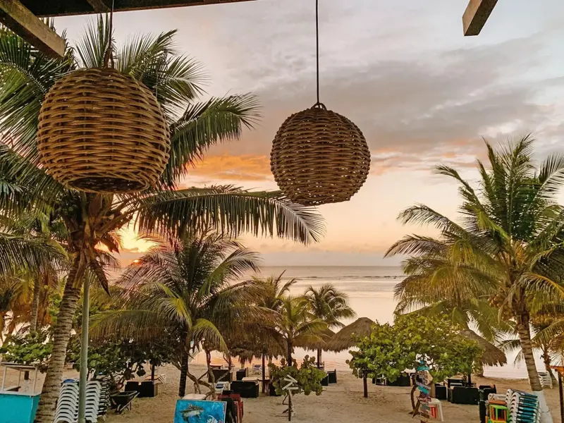 Deux luminaires suspendus au-dessus d'une plage de sable fin au coucher du soleil.