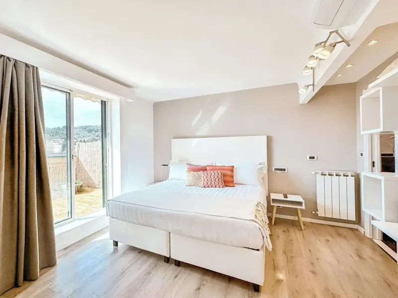 Une chambre lumineuse avec un grand lit et un accès à une terrasse.