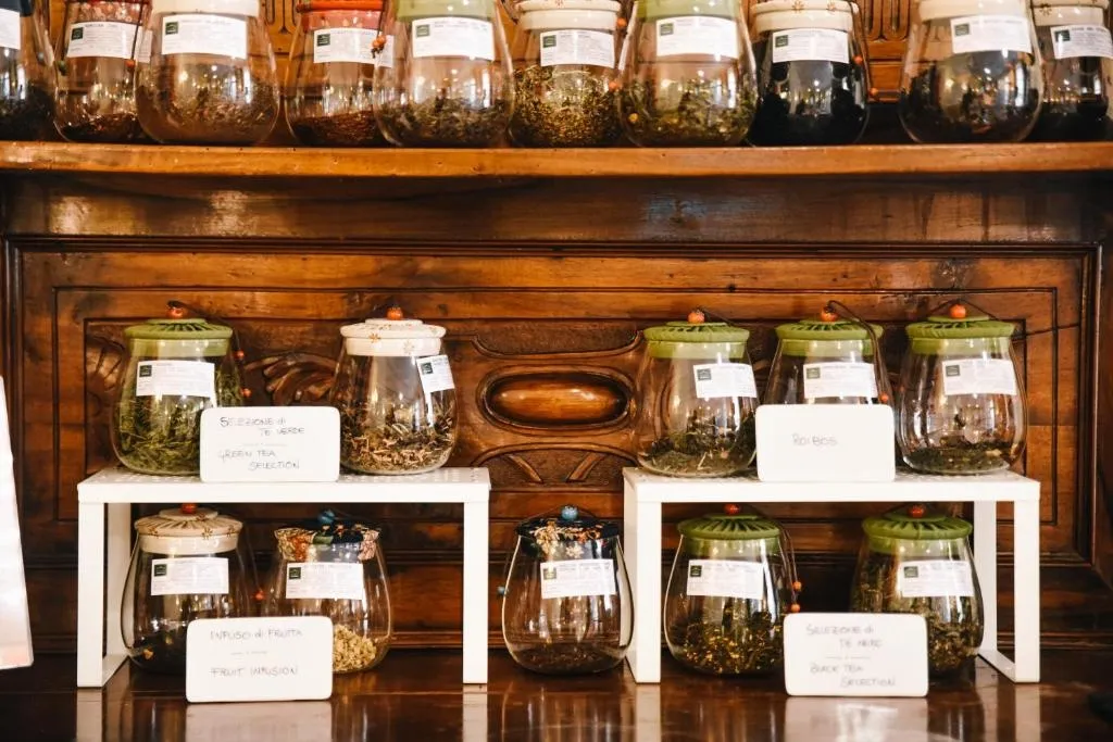 Des bocaux en verre remplis de feuilles de thé sont exposés sur des étagères en bois.