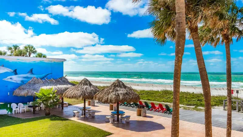 Vue d'une plage ensoleillée avec des parasols en chaume et des chaises longues.