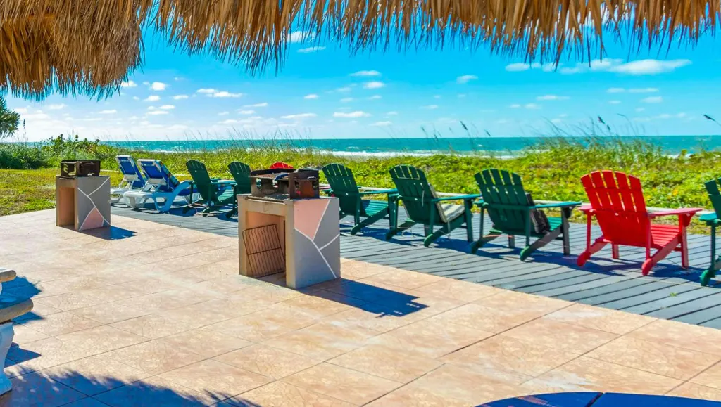 Terrasse en bois avec des barbecues et des chaises longues face à la mer.
