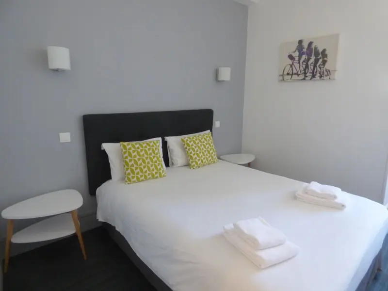 Une chambre lumineuse avec un grand lit recouvert de linge blanc.