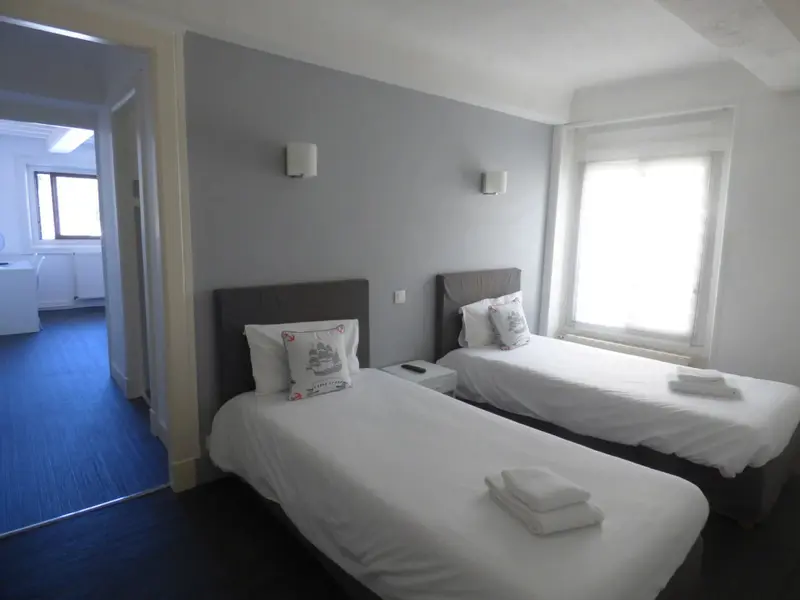 Une chambre lumineuse avec deux lits simples et une fenêtre.