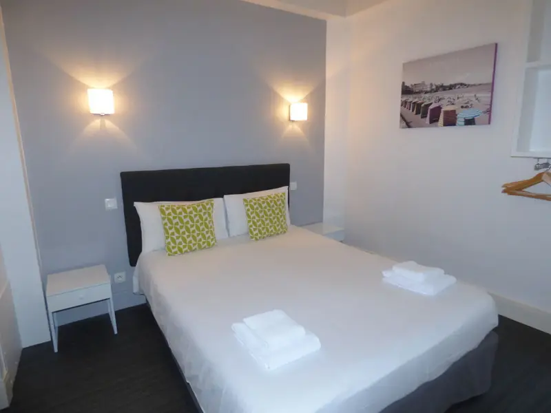 Une chambre lumineuse avec un grand lit recouvert de draps blancs.