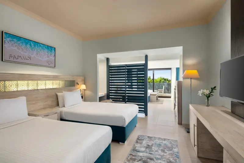 Une chambre lumineuse avec deux lits simples et un accès à un espace extérieur.