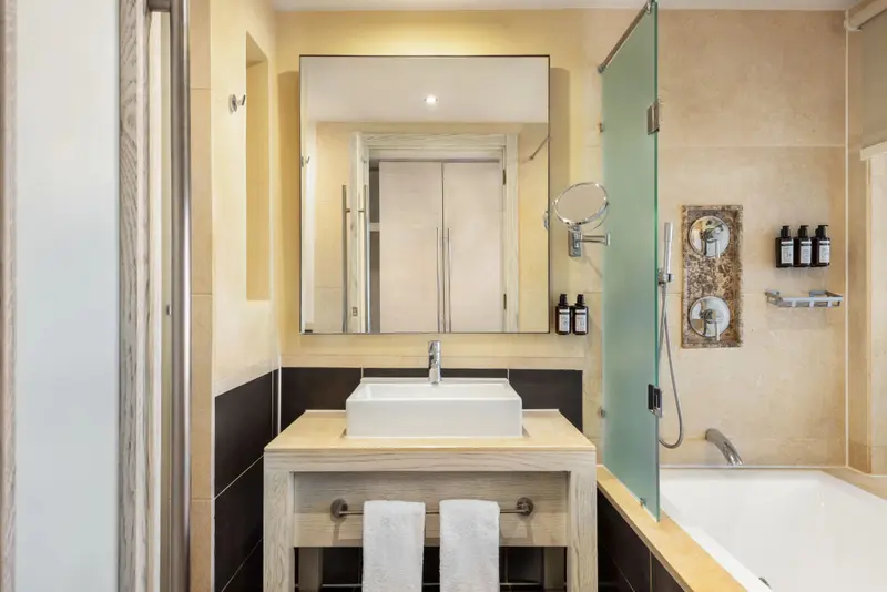 Une salle de bain lumineuse avec une baignoire et un grand miroir.