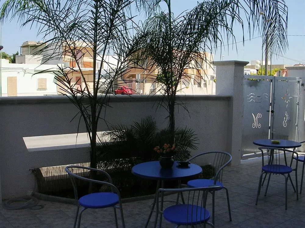 Petites tables bleues et chaises métalliques sur une terrasse ensoleillée.