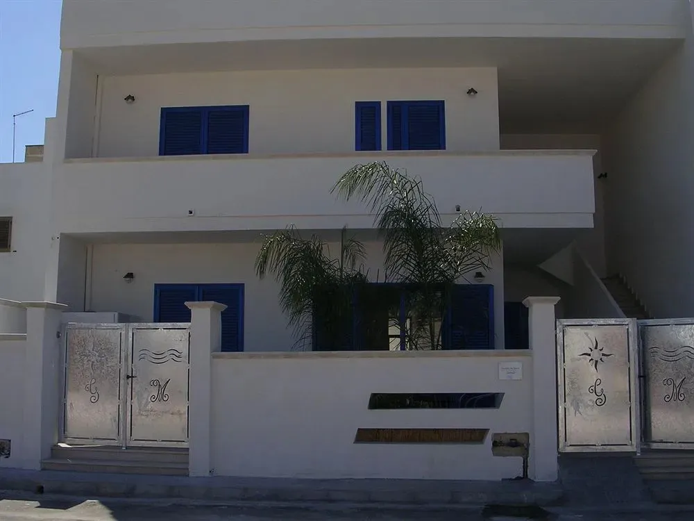 Facade blanche d'un bâtiment avec des ouvertures bleues et une palmeraie.