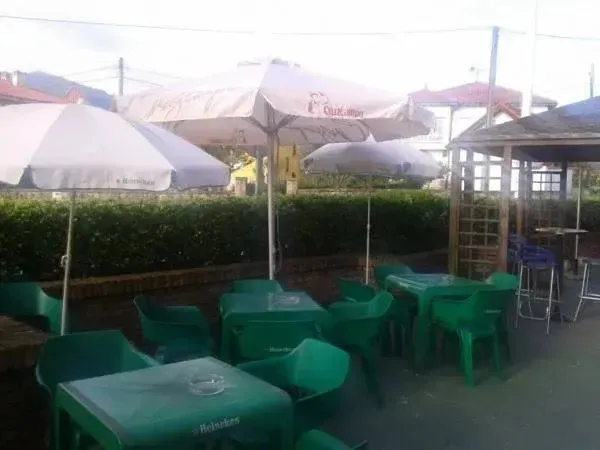 Terrasse ombragée avec tables et chaises vertes.
