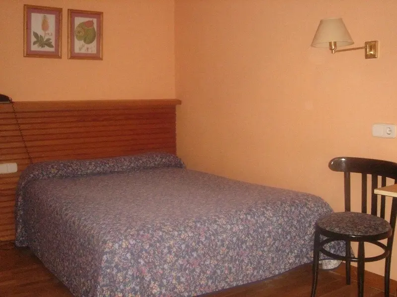 Une chambre aux murs couleur pêche avec un lit recouvert d'une courtepointe à motifs.