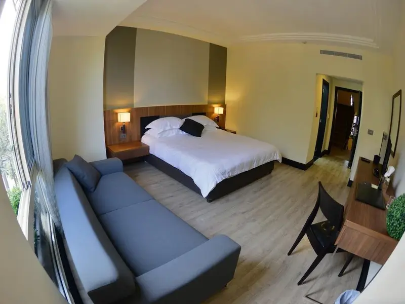 Une chambre lumineuse avec un grand lit et un canapé d'angle.