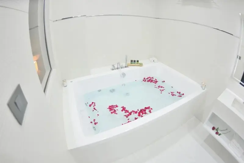 Une baignoire remplie d'eau claire et de pétales de fleurs rouges.