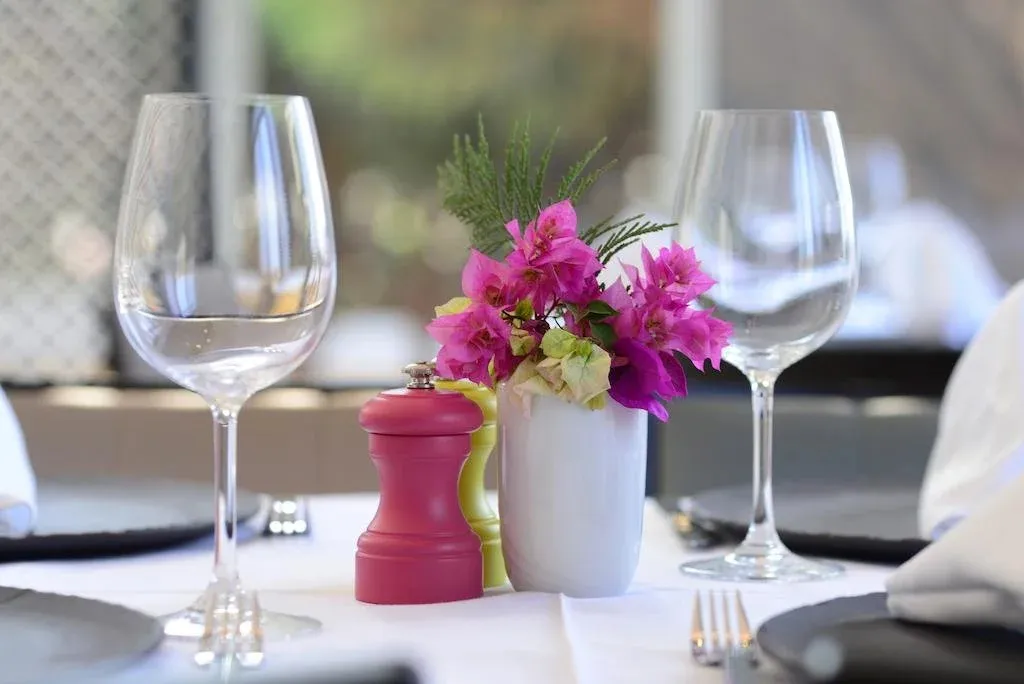 Une table est dressée avec des couverts, des verres et un arrangement floral.
