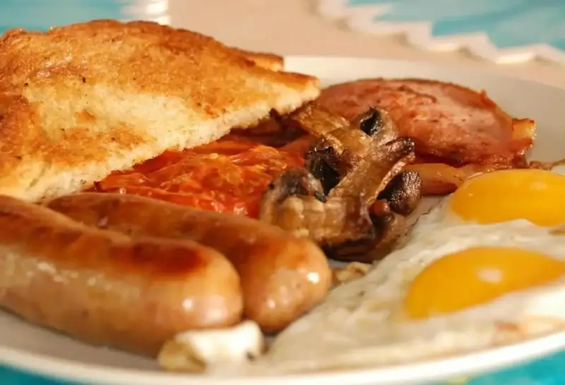 Un petit-déjeuner anglais copieux est présenté sur une assiette blanche.