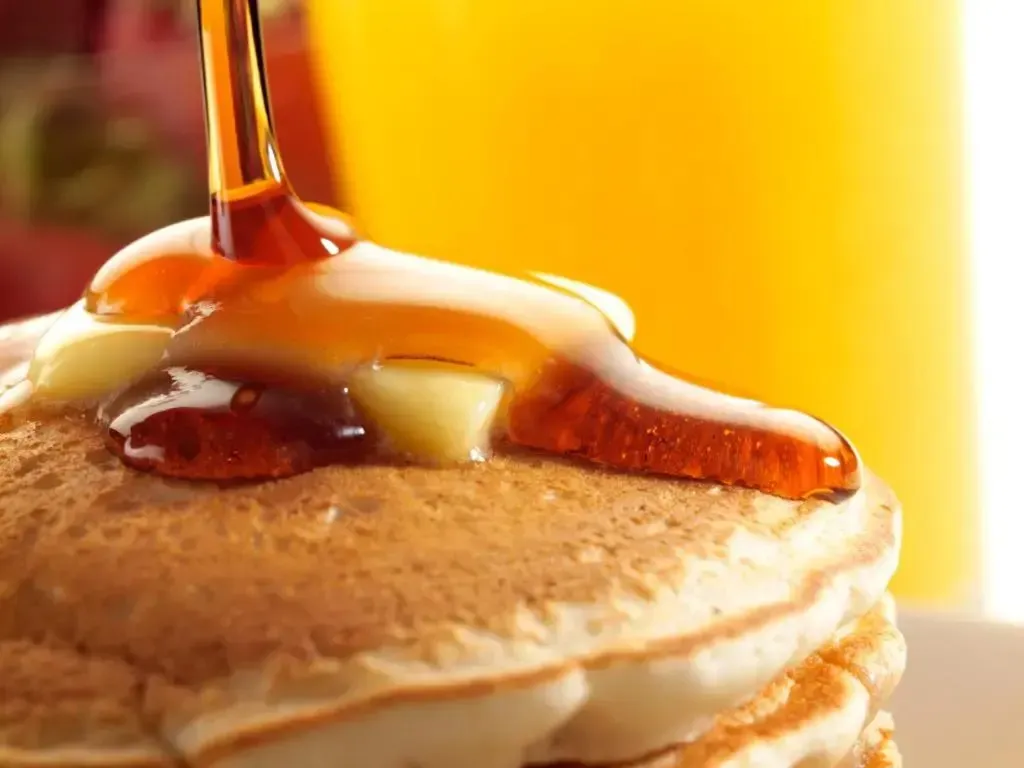 Crêpes empilées nappées de sirop doré et de beurre.