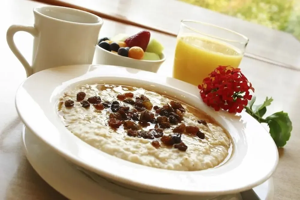 Un bol de porridge aux fruits et une boisson fraîche sont présentés sur une table.