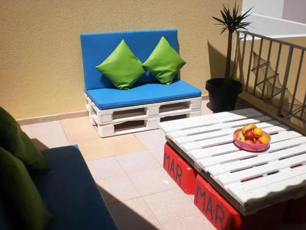 Espace extérieur aménagé avec des meubles en palettes et des coussins colorés.