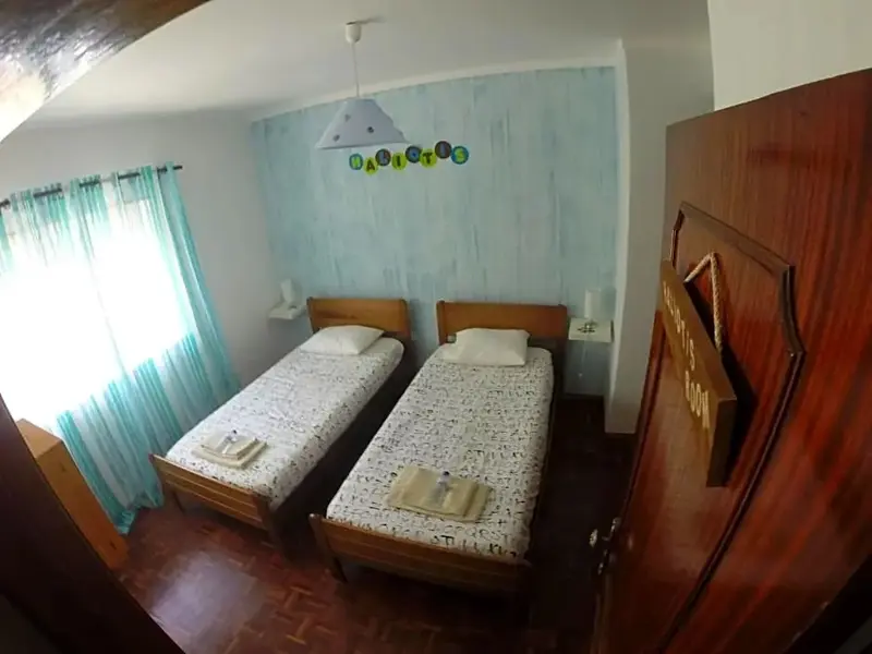 Une chambre avec deux lits simples et un grand placard en bois.