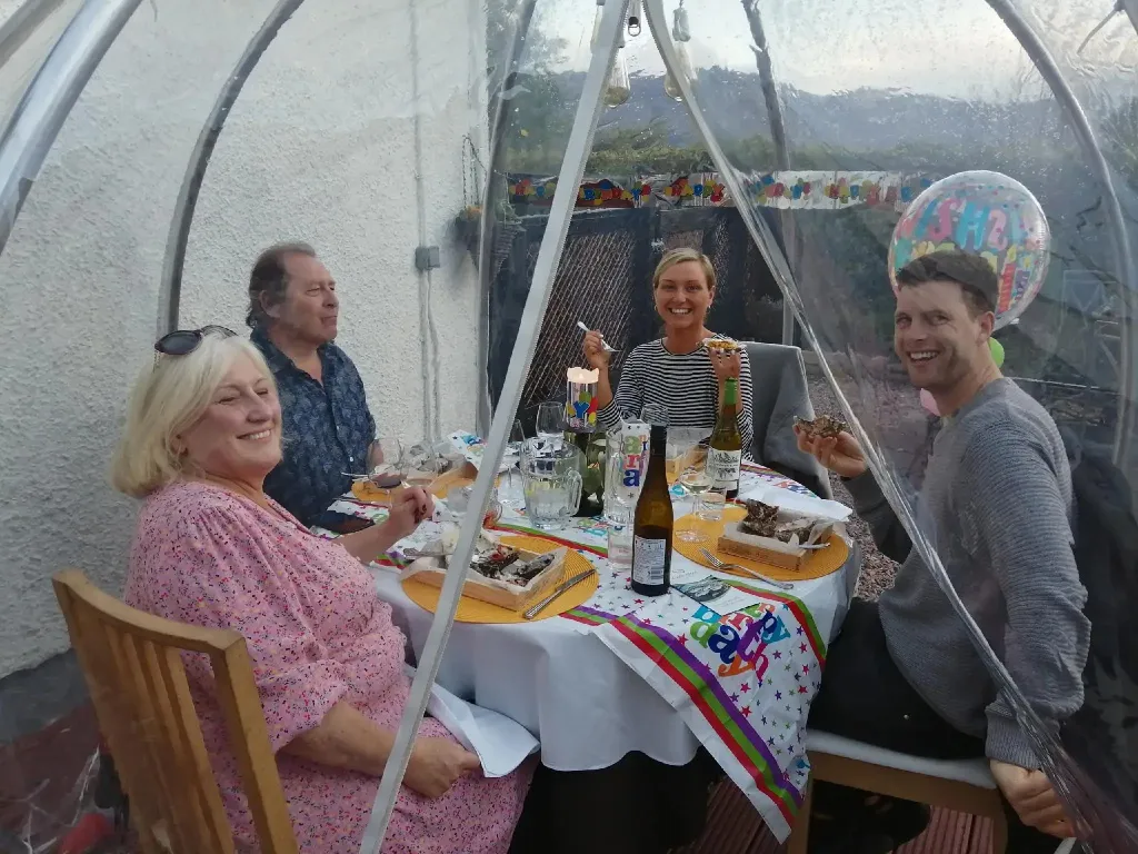 Quatre personnes sourient autour d'une table décorée pour une célébration.
