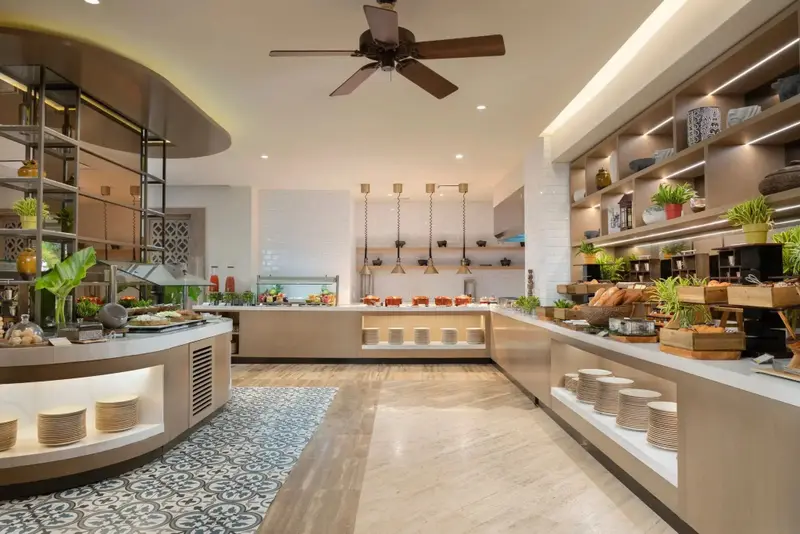 Un buffet propose une variété de plats et de pâtisseries dans une salle lumineuse.